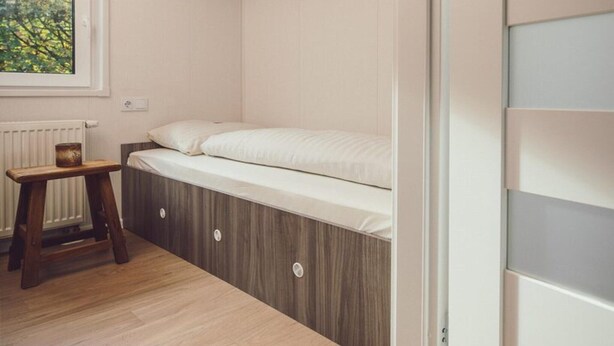 A room with a bed, a small wooden stool, and a radiator. - Modern Cottage with Wood Hot Tub (Rijssen)