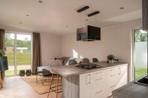 Cozinha moderna com ilha central, área de jantar com cadeiras e uma grande porta de vidro deslizante para o exterior.