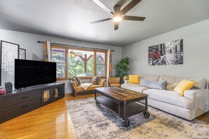 Ein Wohnzimmer mit Fernseher, Sofa, Couchtisch und Deckenventilator.