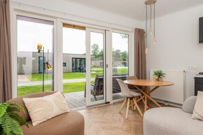 Een moderne woonkamer met een bank, een eettafel en een schuifpui naar een terras.