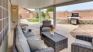 An outdoor patio with a sofa, chairs, and a grill.