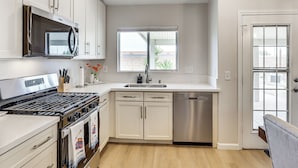 A modern kitchen with white cabinets, a stainless steel stove, a microwave, and a dishwasher.