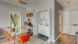 Eine moderne Küche mit weißen Schränken, einem Glastisch und orangen Stühlen.