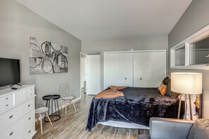 Ein Schlafzimmer mit Bett, Fernseher, Schreibtisch, Stuhl, Lampe und Kleiderschrank.
