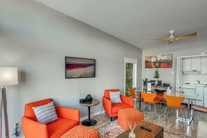 Ein modernes Wohnzimmer mit orangefarbenen Möbeln, einem Essbereich und einer Küche.
