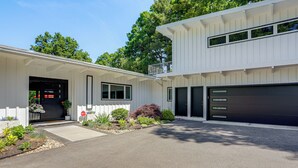 Ein modernes, zweistöckiges Haus mit Garage, Veranda und einem angelegten Garten.