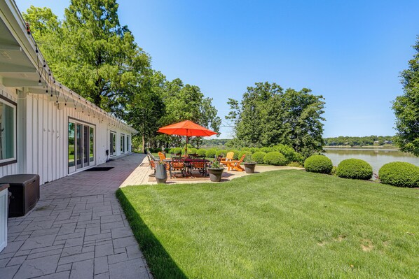 Eine Terrasse mit Gartenmöbeln, einem Tisch und Stühlen, umgeben von einem gepflegten Rasen und Bäumen.