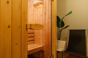A wooden sauna with a bench, a potted plant, and a blackboard.
