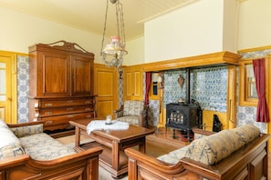 A traditional room with a wooden cabinet, a sofa, a table, and a fireplace.