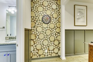 Ein Zimmer mit einer Wand, die mit kreisenden Holzmustern, einem Dartspiel und einem gerahmten Diagramm verziert ist.