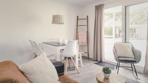 Een moderne woonkamer met een eethoek, een ladder en uitzicht op de omgeving.