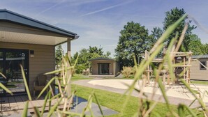 Een woonwijk met een huis, een tuinhuisje en een speeltuin.
