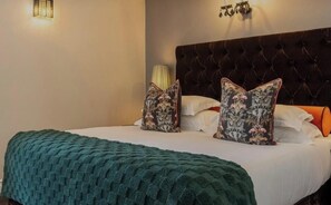 A hotel room with a tufted headboard, a green knitted throw blanket, and floral-patterned pillows. - Maximum 2 people and kids under 6 stay for free (Cape Town)