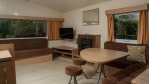 Ein modernes Wohnzimmer mit Sofa, Fernseher, Kamin und Esstisch.