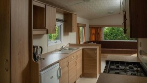 Eine kleine Küche mit Holzausstattung, einem eingebauten Herd und einem Fenster mit Blick auf Grünflächen.