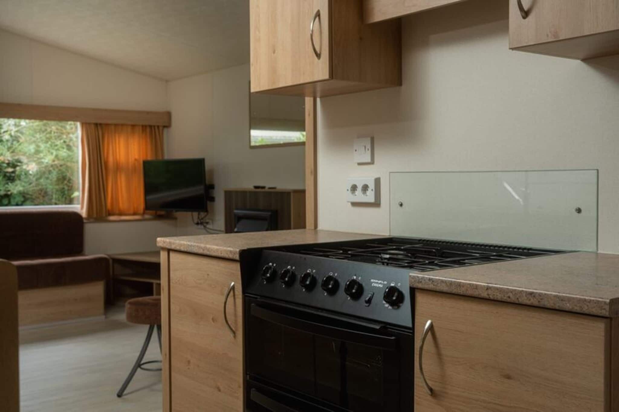 A compact kitchen with a stove, oven, and wooden cabinets.