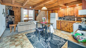 Ein rustikales Blockhaus-Interieur mit Kamin, Holztisch, Sofa und Küchenzeile.