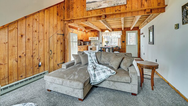 Ein gemütliches Wohnzimmer mit einer Eckcouch, einem kleinen runden Tisch und Holzvertäfelung an den Wänden.