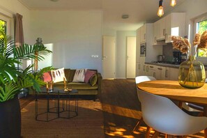 Een moderne woonkamer met een bank, salontafel en een eethoek met een tafel en stoelen.