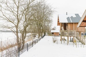 Una cabaña de madera con un porche cubierto de nieve y techo de metal.