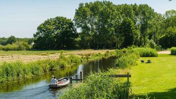 A river with a boat, surrounded by greenery and trees.