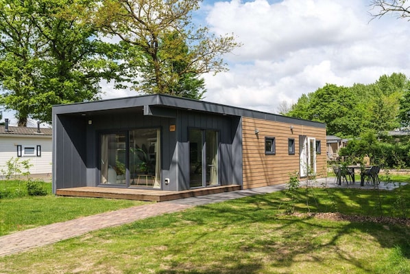 A modern single-story house with a large glass door entrance, a small porch, and a paved driveway.