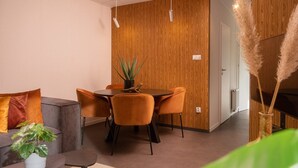 Et moderne interiør med spiseplads, sofa og en plante.