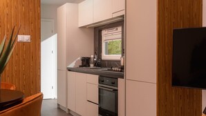 Et moderne køkken med træskabe, en indbygget ovn og et vindue med rullegardiner.