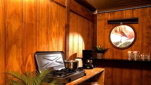 Una cocina con estufa, una olla, una cafetera y un espejo redondo en la pared.