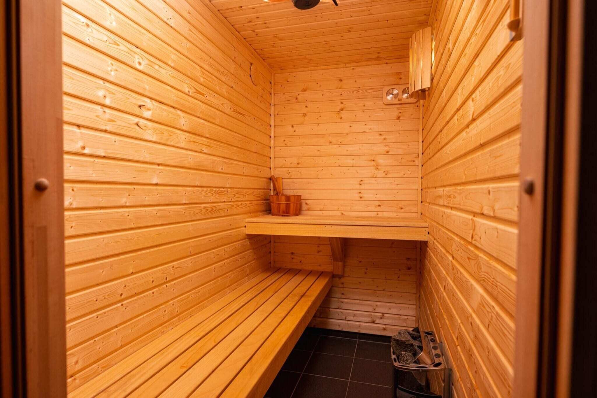 A sauna with wooden walls and benches, a shelf, and a tiled floor.