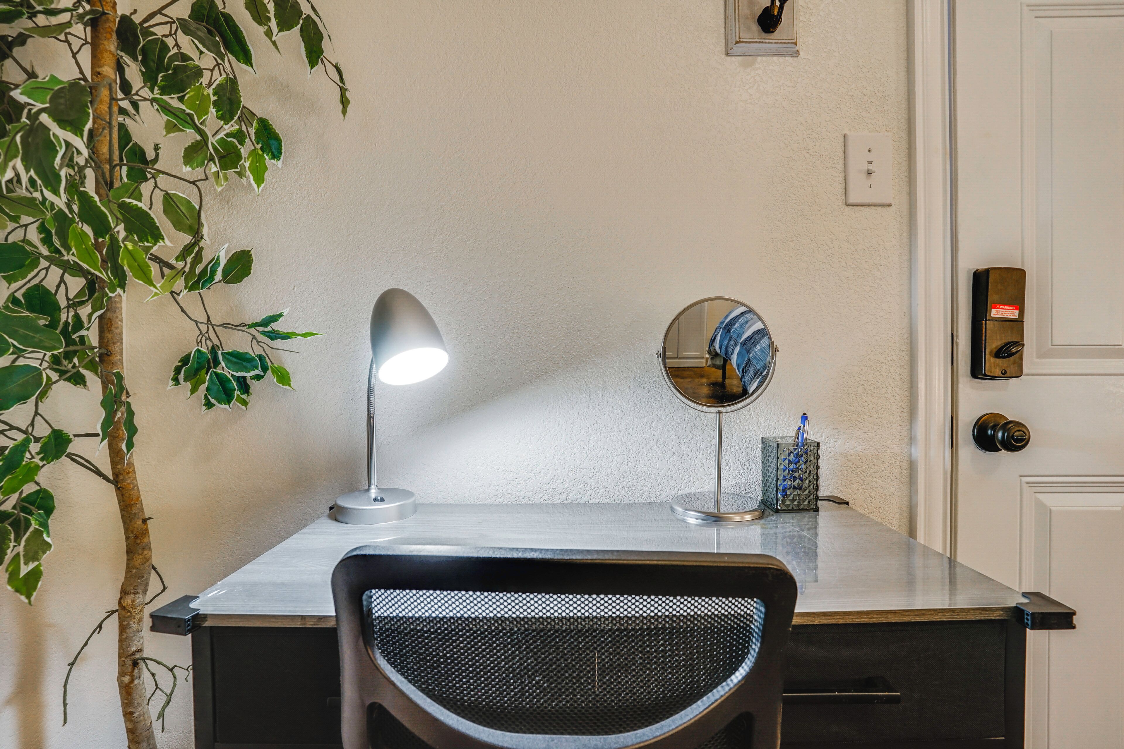 A desk with a lamp, a mirror, and a plant.