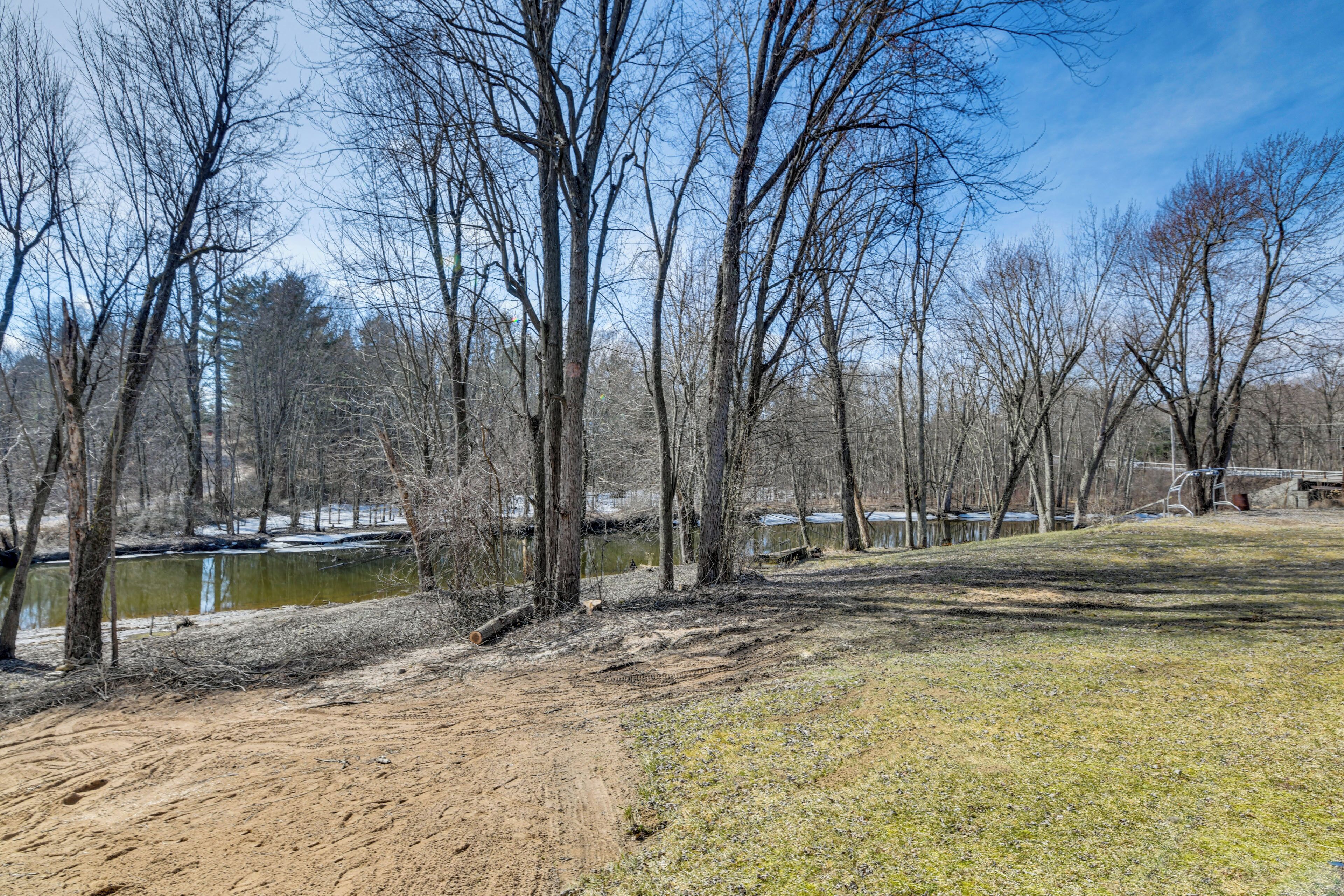 A park with a dirt path, trees, and a body of water.