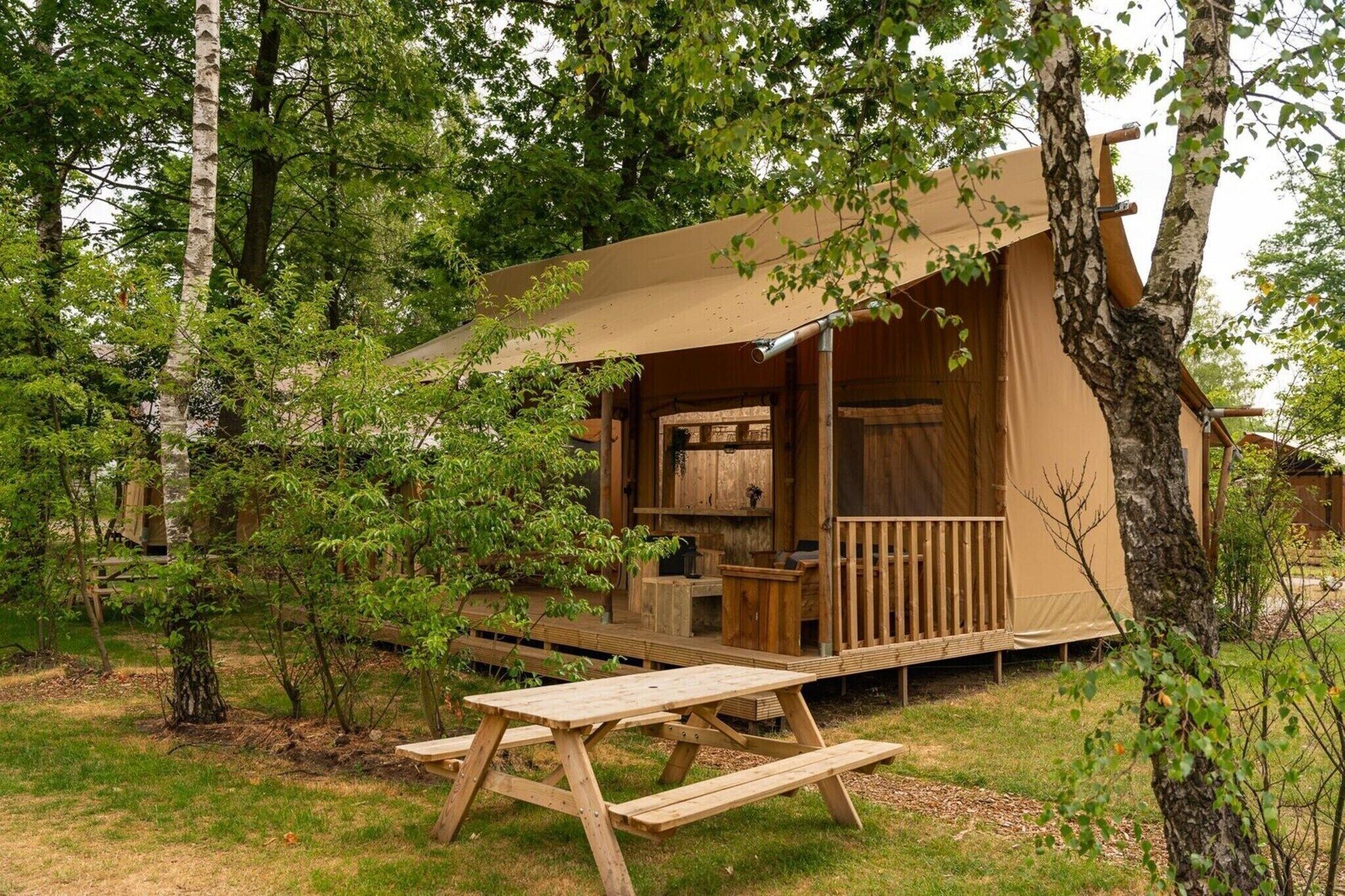 A wooden cabin with a deck, surrounded by trees.