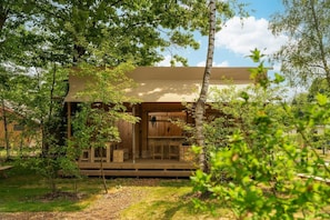 Une cabane en bois avec une terrasse, entourée d’arbres.