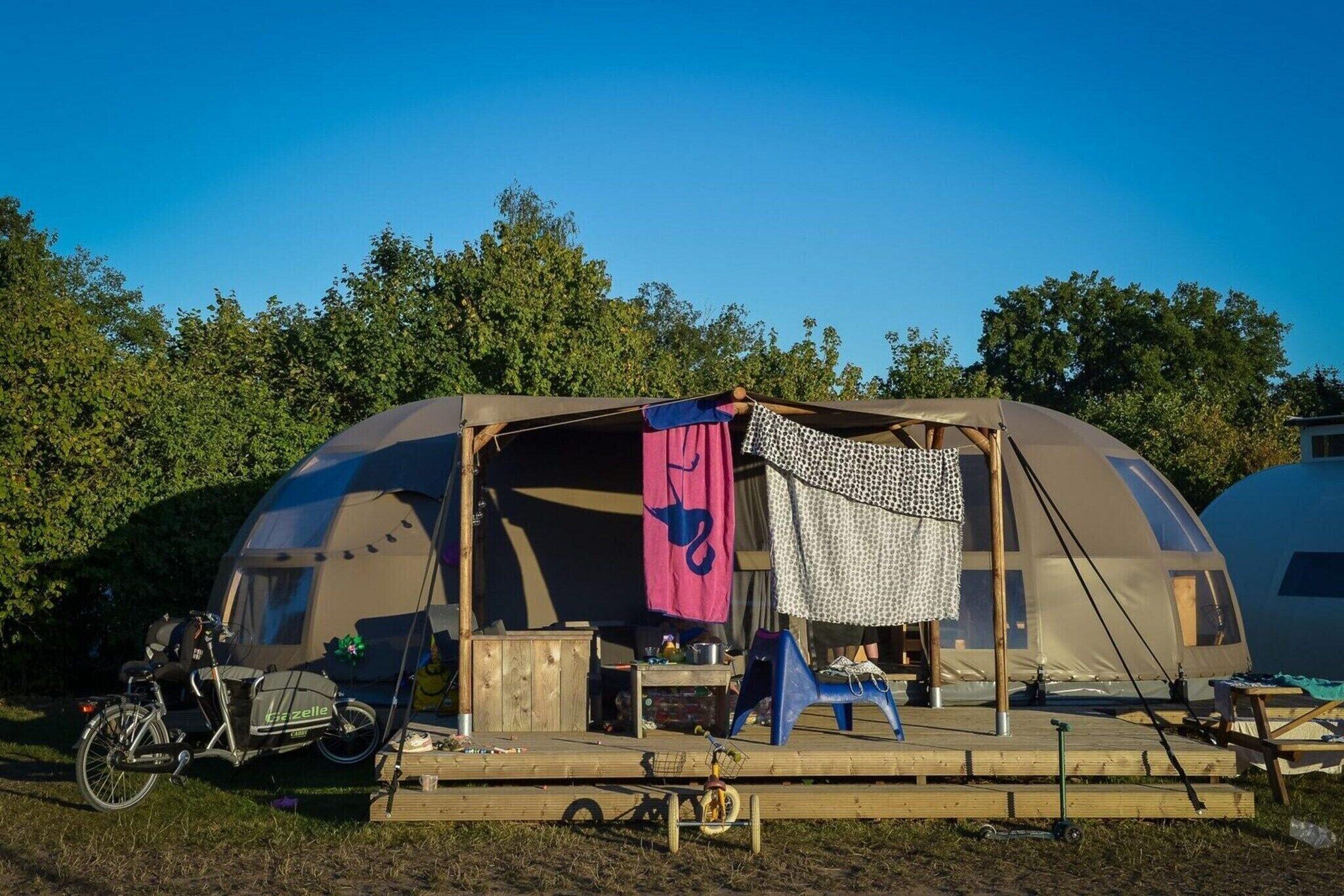 A dome-shaped tent with a covered porch, a bicycle, and a small table.