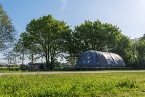 Una construcció amb forma de cúpula i un sostre transparent, envoltada per un camp de gespa i arbres.