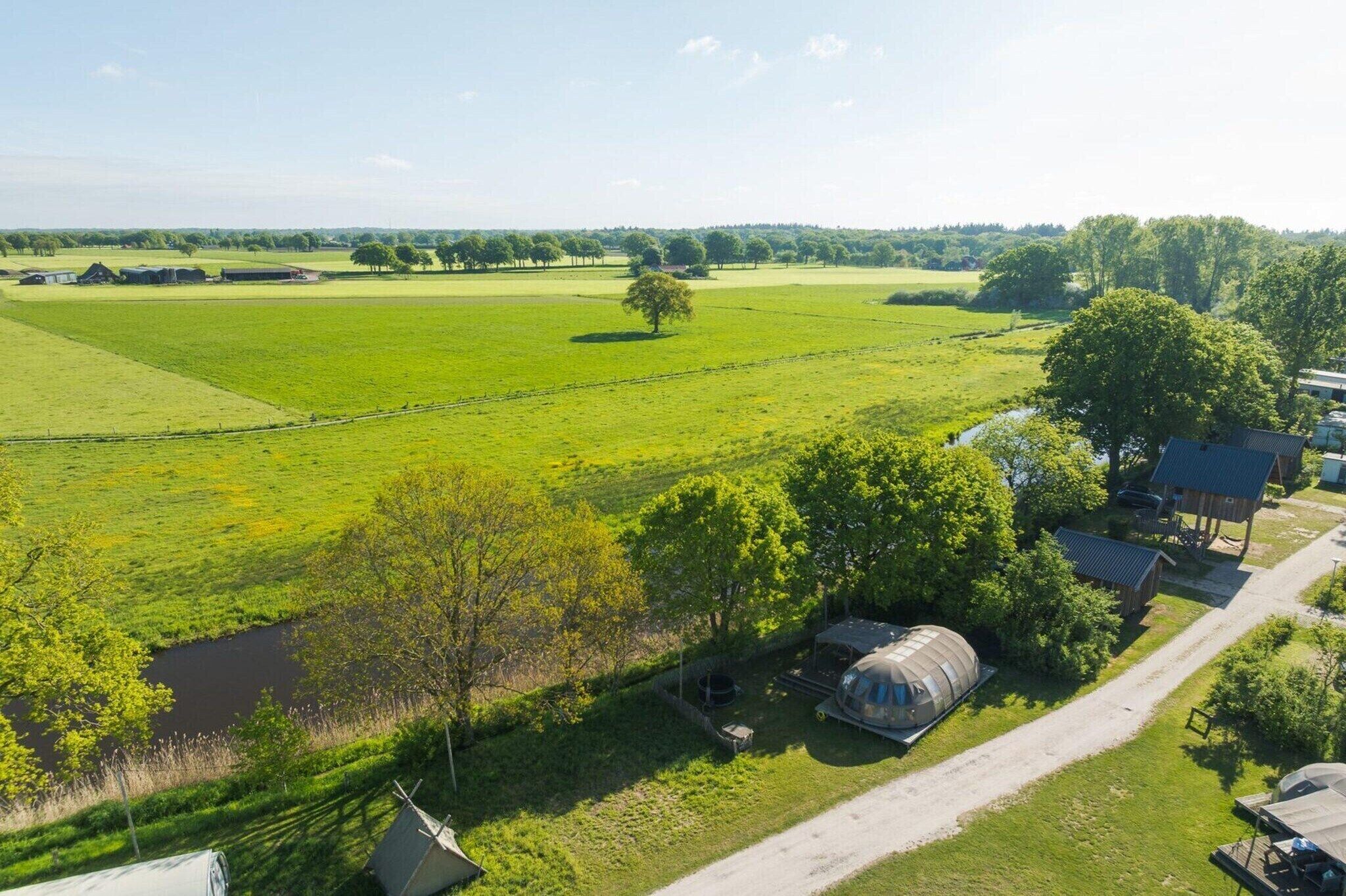 A rural landscape with open fields, a small building, and a large cylindrical structure.
