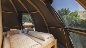 A tent-style room with two beds, a window, and a view of trees. - Unique Riverdome Stay with Hot Tub (Zuna)