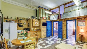 A compact kitchen with wooden cabinets, a dining table, and a checkered floor. - 'Old School ATV Retreat' On Warrior Trail, 8BR (Gary)