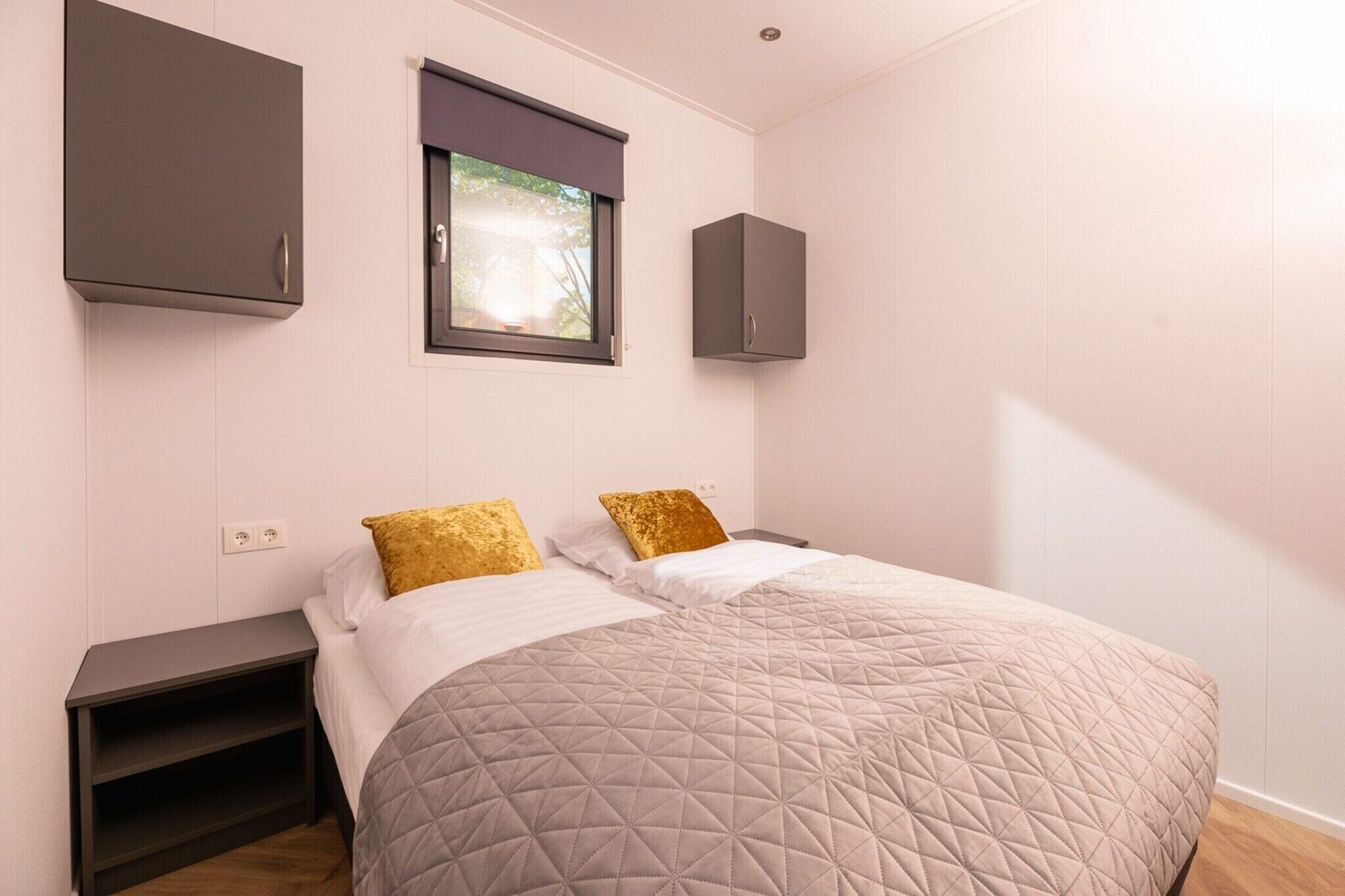 A bedroom with a bed, two nightstands, a window with blinds, and built-in cabinets.
