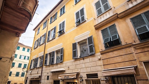 A yellow building with multiple windows and a closed shutter door. - Hotiday Rapallo Old Town (Rapallo)