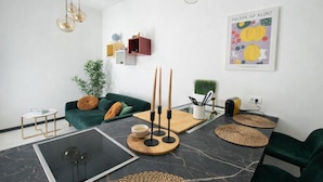 A modern living room with a green sofa, a glass coffee table, a marble floor, and a wall-mounted light fixture. - Hotiday Rapallo Old Town (Rapallo)