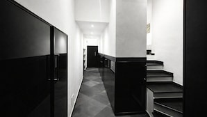 A modern hallway with a staircase, a door at the end, and a light fixture on the ceiling. - Hotiday Rapallo Old Town (Rapallo)