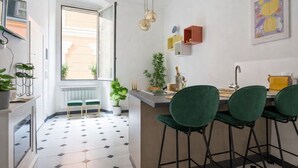 A modern kitchen with a dining area, featuring a large window, green chairs, and a minimalist design. - Hotiday Rapallo Old Town (Rapallo)