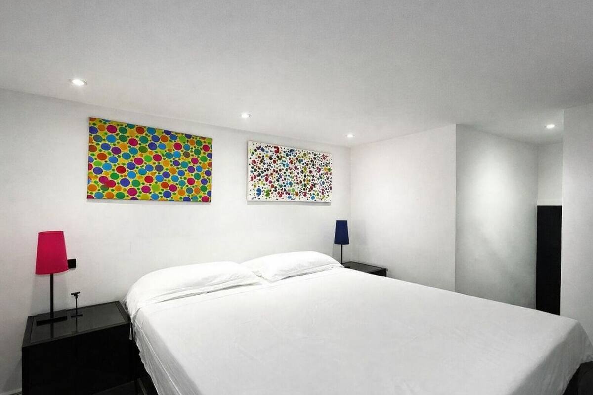 Ein modernes Hotelzimmer mit einem großen Bett, zwei Nachttischen und zwei Wandlampen.