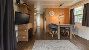Een moderne keuken met een ingebouwde televisie, houten kastjes en een eethoek met een tafel en stoelen.
