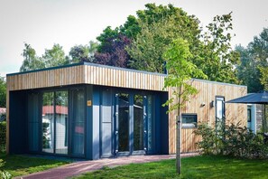 A modern building with large glass doors, a wooden exterior, and a pathway leading to it.
