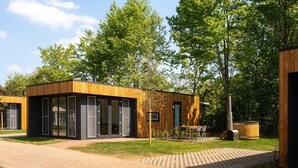 En modern byggnad med stora glasfönster, en träfasad och en stenlagd gångväg.