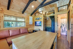 A wooden interior with a wooden table, a bench, and a television.