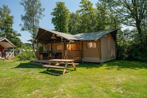 Une cabane rustique dotée d’un porche couvert, d’une table de pique-nique et d’une petite terrasse.